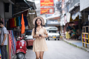 Obraz premium A woman wearing a hat and a dress is walking down a street
