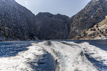 Speed boat leaving beautiful Pedi bay and idyllic beach on Symi island, Greece