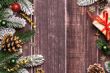 Beautiful Christmas border with fir tree branches, pine cones and shining decorations on dark...