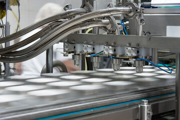 Close-up automated filling of cheese mass, sour cream or yoghurt into packages. Food production, dairy plant, line