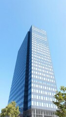 Obraz premium Modern office building with glass facade standing tall against a clear blue sky, business district