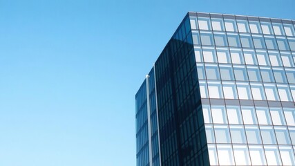 Modern office building with sleek glass facade against a clear blue sky backdrop, background