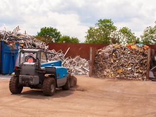 Scrap brass separated in a bay ready to be loaded into a container for export. Loading shovel in scrap yard.