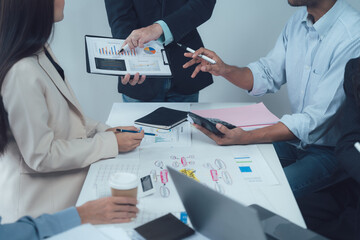 Strategic Business Meeting: Diverse team collaborating around a table, analyzing data and charts, showcasing modern workplace synergy and innovative problem-solving.