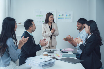 Celebrating Success: A diverse team applauds a female leader during a productive meeting, showcasing collaboration and achievement in a modern office setting. 