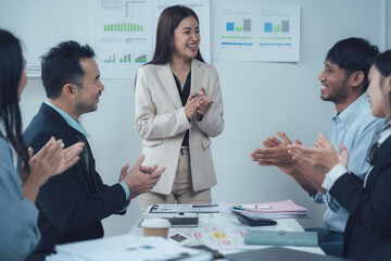 Appreciation and Collaboration: A diverse team of business professionals applauds a female colleague in a modern office setting, showcasing a positive and supportive work environment.  