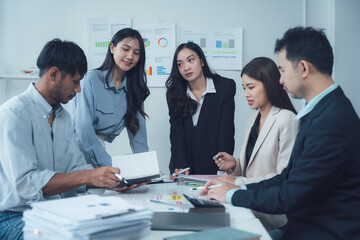 Teamwork Makes the Dream Work: A diverse group of young business professionals collaborates around a table, engaged in a serious discussion over documents and charts.