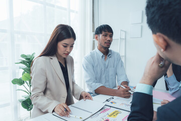 Business Professionals in a Meeting:  A diverse team of business professionals engaged in a serious discussion, focused and attentive as they review documents and strategize together.