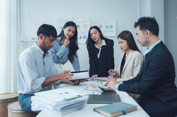 Collaborative Brainstorming: A diverse team of professionals engaged in a lively brainstorming session, analyzing data and ideas on a digital tablet. They are surrounded by a vibrant workplace.