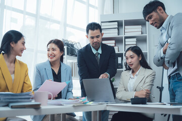 Teamwork Makes the Dream Work: A diverse group of business professionals collaborates around a laptop, showcasing teamwork, strategy, and modern office dynamics.  