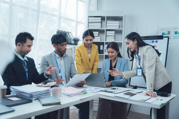 Collaborative Brainstorming: A diverse team of professionals huddle around a laptop, engaged in a lively discussion, fueled by ideas and a shared goal.  The office setting.