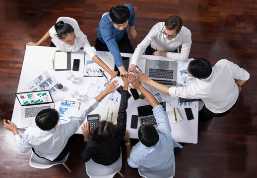 Top view diverse office worker join hand together in office room symbolize business synergy and strong productive teamwork in workplace. Cooperation and unity between business employee. Prudent