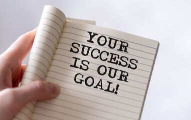 Your success is our goal text on blank business card being held by a woman's hand with blurred...