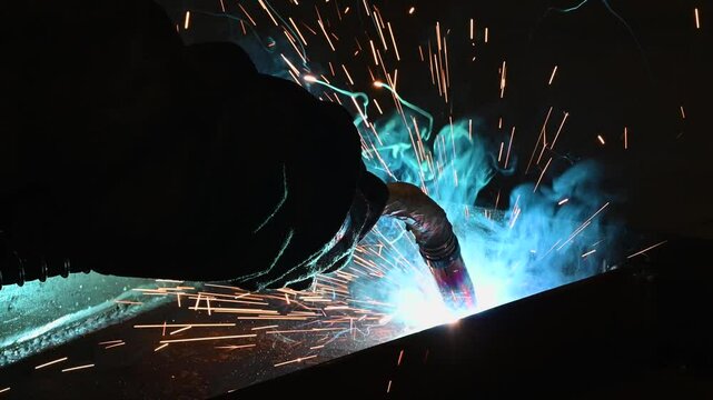 Factory worker welding steel parts together with a welding machine