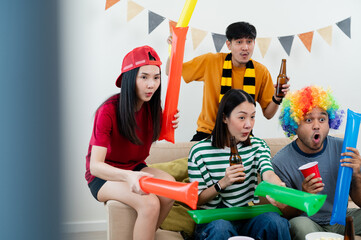 A group of Asian male and female friends excitedly watched the World Cup match on TV. and eat beer and snacks together at home Sports fans shout and celebrate the victory of their sports team.