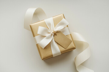 Fototapeta premium Elegant gold gift box with a ribbon, placed on a white background, showcasing a festive and refined holiday gift.