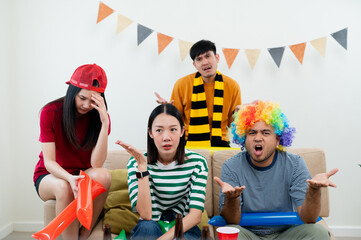 A group of Asian male and female friends watch the live broadcast of the World Cup match on television. Share a beer and snacks together at home. Sports fans feel sad when the team they support loses.