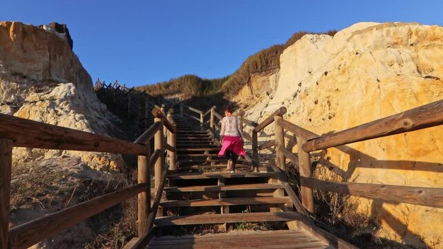 Mature woman on a walkway with wooden steps on Cuesta Maneli beach, located in a very unique environment, the fossil dune system of El Asperillo, located within the Do&ntilde;ana Natural Park, Huelva, Spain.
