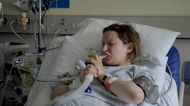 Woman in visible pain inhaling gas to manage birthing contractions, capturing a powerful moment of labor in a hospital environment