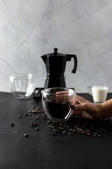 
Black coffee is poured into a cup, on a black background. pour milk into coffee