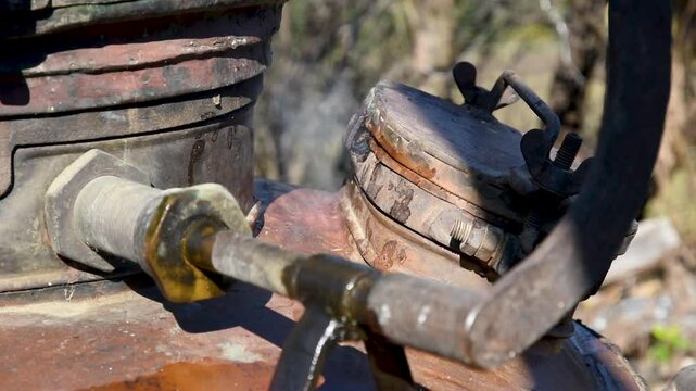 Hot steam escapes from under boilers lid of brandy cauldron close up, poor seal