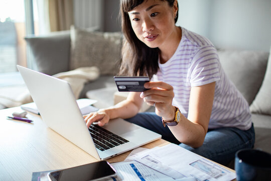 Asian woman online shopping with credit card and laptop at home