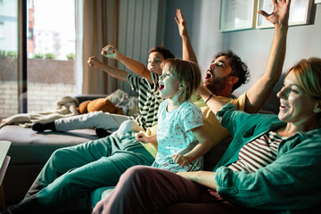 Family cheering while watching tv at home on the couch
