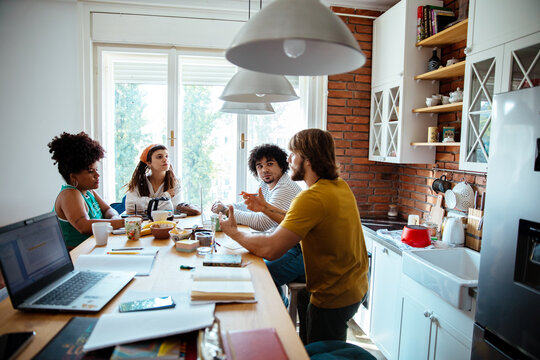 Group of friends studying and eating pizza together at home