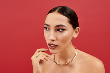 A young woman with a striking look showcases her beauty in a vibrant red setting.
