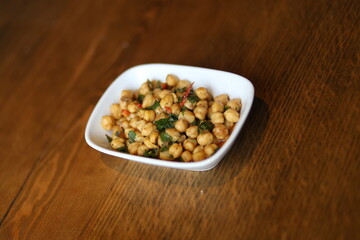 A close-up of a delicious and healthy Turkish appetizer, featuring roasted chickpeas with herbs and spices, served in a white bowl