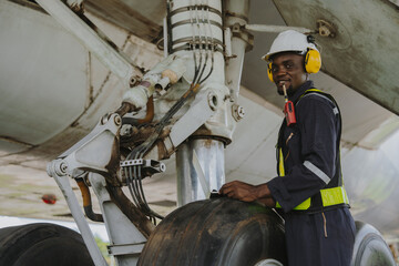 Mechanics inspect the engines of a large plane before takeoff at a summer airport.