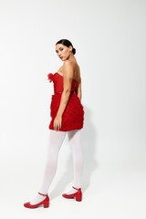 A stylish young woman showcases a playful red dress and matching shoes with elegance and flair