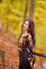 a beautiful woman with a scarf in her hand is enjoying the autumn landscape