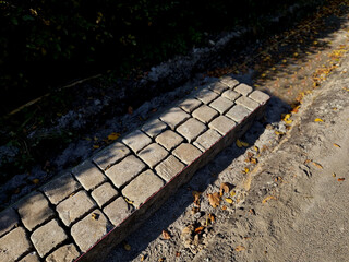 the edge of the road is formed by a stone border, a pavement made of paving stones laid in a straight line according to a string. the concrete sticks around the pavement