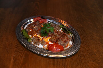 A mouthwatering platter of Turkish Adana kebab, served with fresh tomatoes, green peppers, and a dollop of creamy yogurt