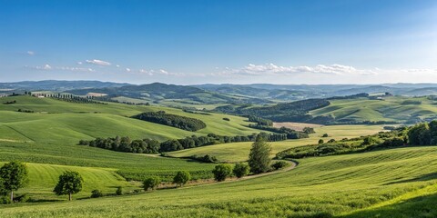Obraz premium Panoramic view of a serene countryside with rolling hills, green fields, and a blue sky, agriculture, hillside, clouds, nature, farm