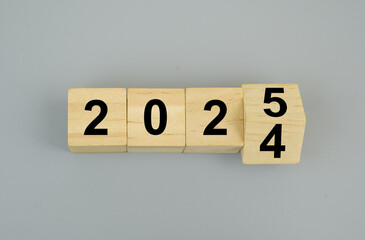 Wooden cubes with numbers 2024 and 2025 on gray background. Flipping of 2024 to 2025.