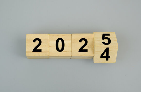 Wooden cubes with numbers 2024 and 2025 on gray background. Flipping of 2024 to 2025.