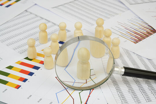 Management, demography and statistics concept. People figures under magnifying glass on financial graphs.