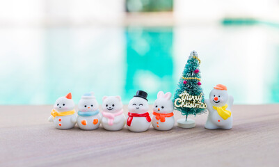 Obraz premium Cute miniature snow man collection with Christmas tree over blurred background, outdoor day light, Christmas card background idea