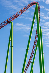 Colored metal roller coaster on a blue sky background on a sunny day.