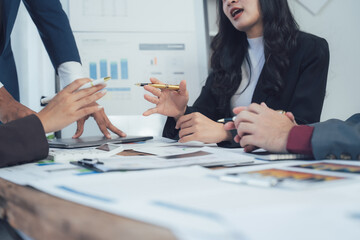 Strategic Collaboration: Business team meeting around a table, engaging in lively discussion and brainstorming. Hands actively involved with documents and digital devices.  