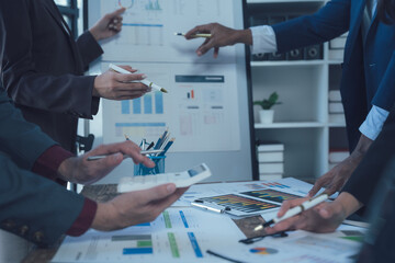 Strategic Collaboration: A diverse team of business professionals collaborates around a table, analyzing data and charts during a strategic meeting.