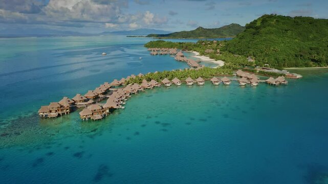 Aerial view zoom out panorama of luxurious overwater bungalows lining the tropical island shore, nestled in vibrant turquoise lagoon in Bora Bora. Popular tourist destination, exotic summer travel