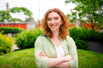 Young redhaired woman enjoying a sunny day outdoors, smiling and feeling relaxed in natural daylight