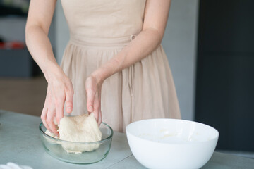 Girl in the kitchen in a beige dress preparing dough