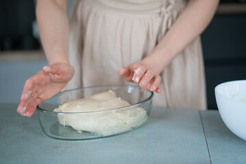 Girl in the kitchen in a beige dress preparing dough