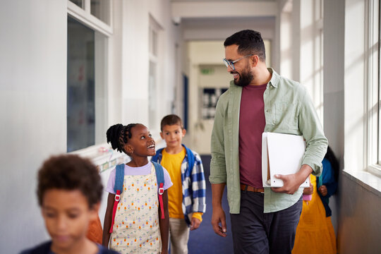 Fototapeta Teacher talking with little girl in primary school hallway