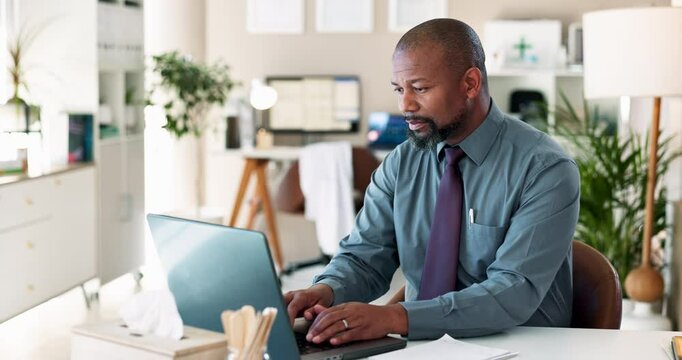 Black man, typing and doctor with laptop or paperwork for report, medical history or notes at office desk. African, healthcare or employee with computer or documents for prescription or checklist