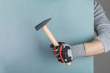 Hand with protective glove holding hammer